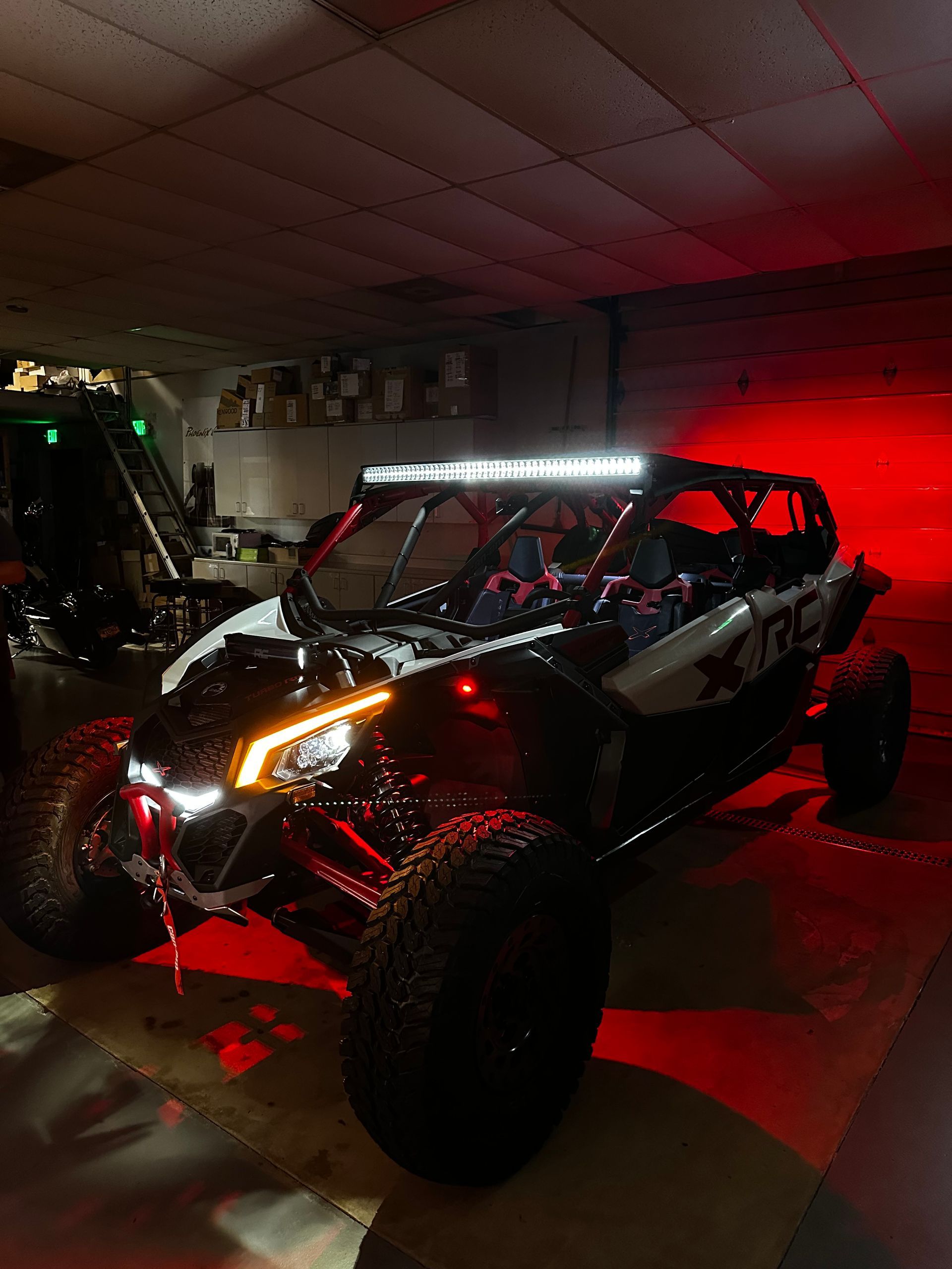 Black off-road buggy with red lights in a garage, viewed from the front-left.