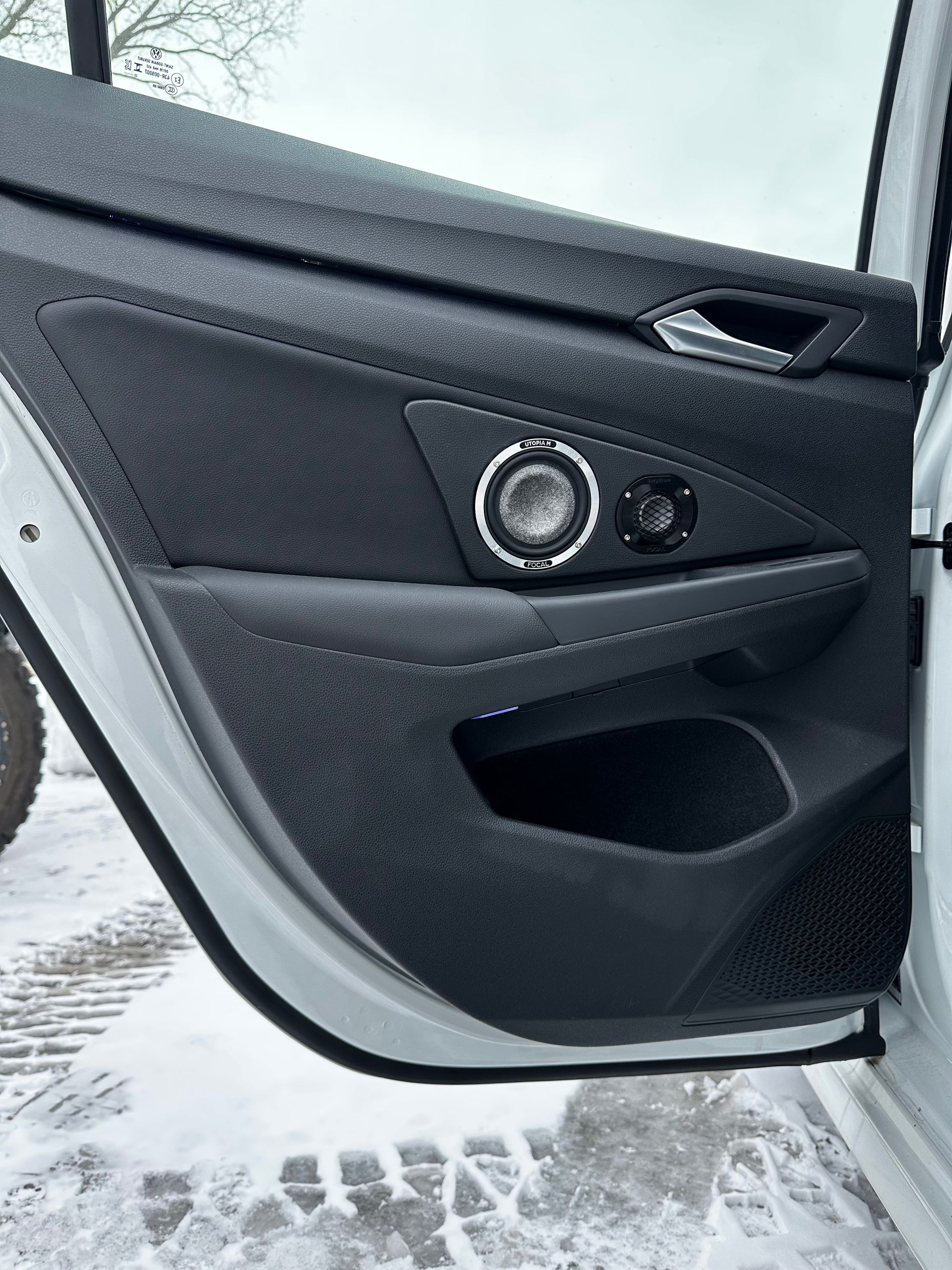 Close-up of a black car’s interior door panel with window controls and handle visible.