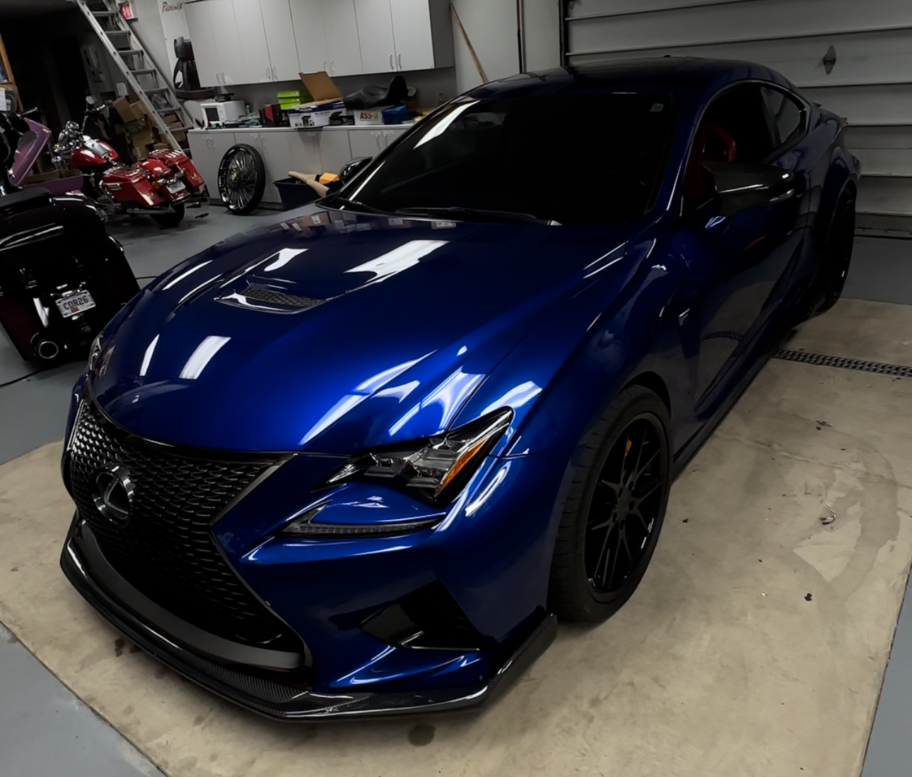Blue sports sedan parked in a garage, showing a front-left angle and glossy finish.