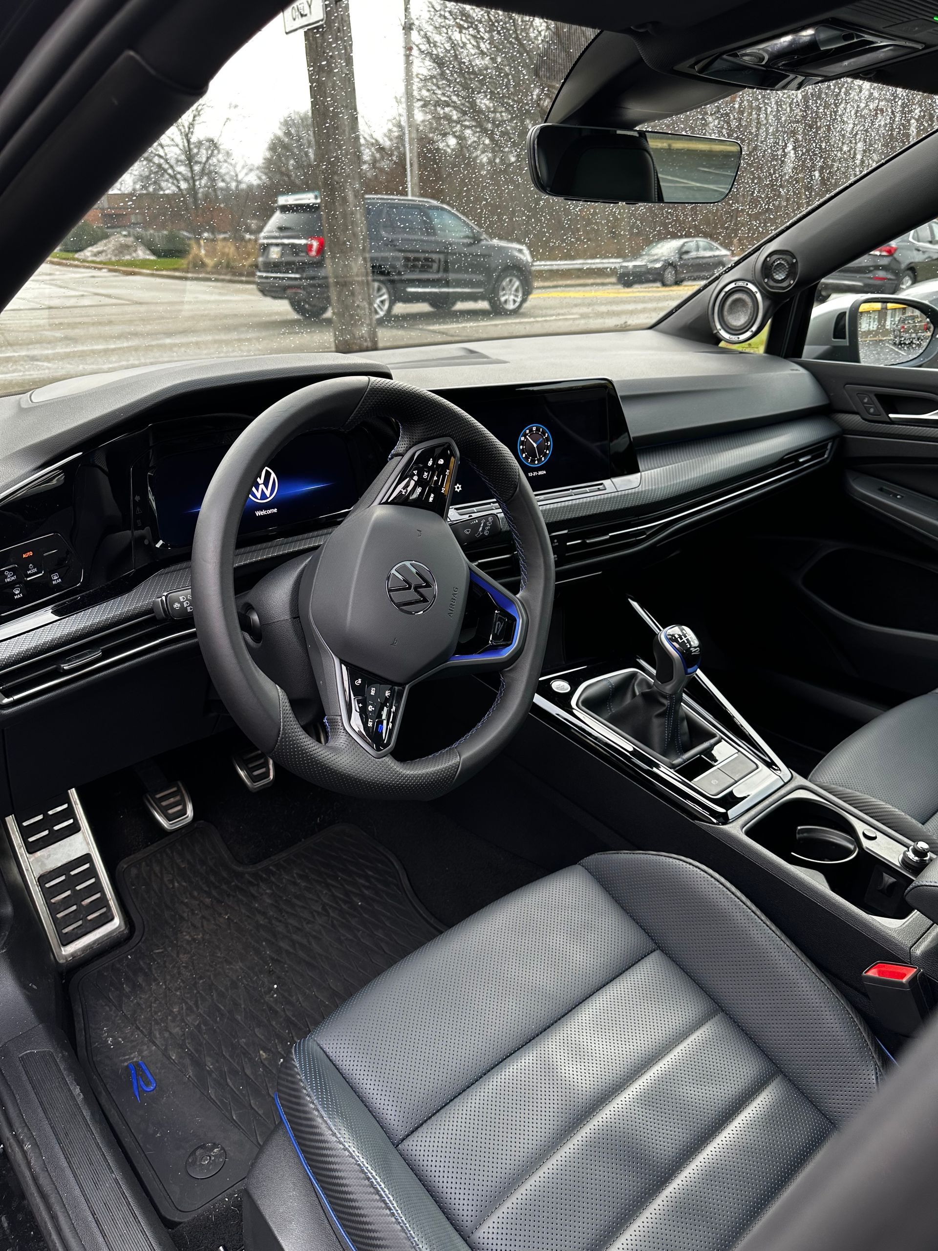 Luxury car interior with black leather seats and dashboard, seen through the front cabin window.
