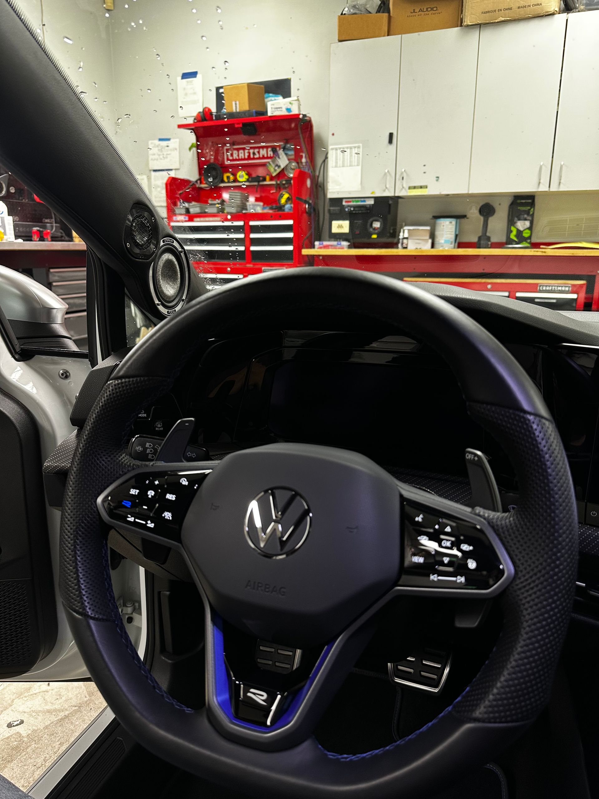 Volkswagen steering wheel in a garage, with red tool cabinets and white storage cabinets in the background