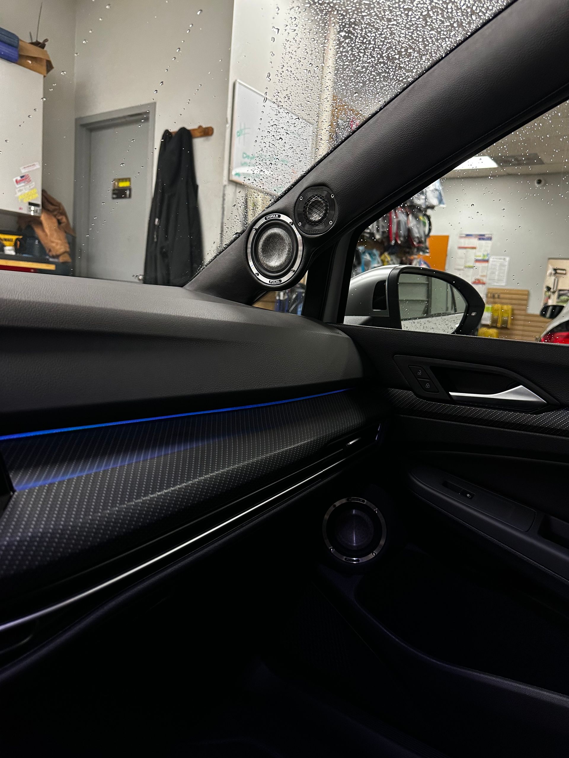 Car interior with black trim and a blue accent light, parked inside a garage.