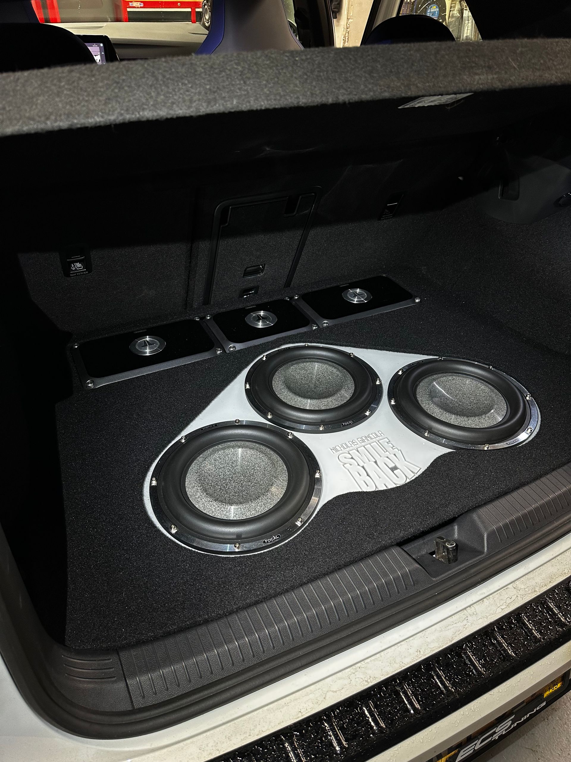 Open car trunk with a large black-and-silver speaker/subwoofer system installed inside