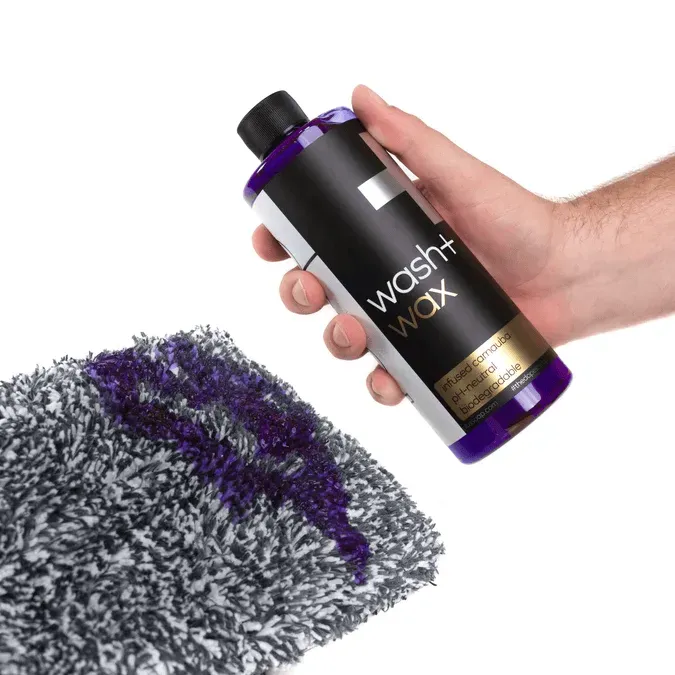 Black wash+ WAX bottle with purple cap on a white background