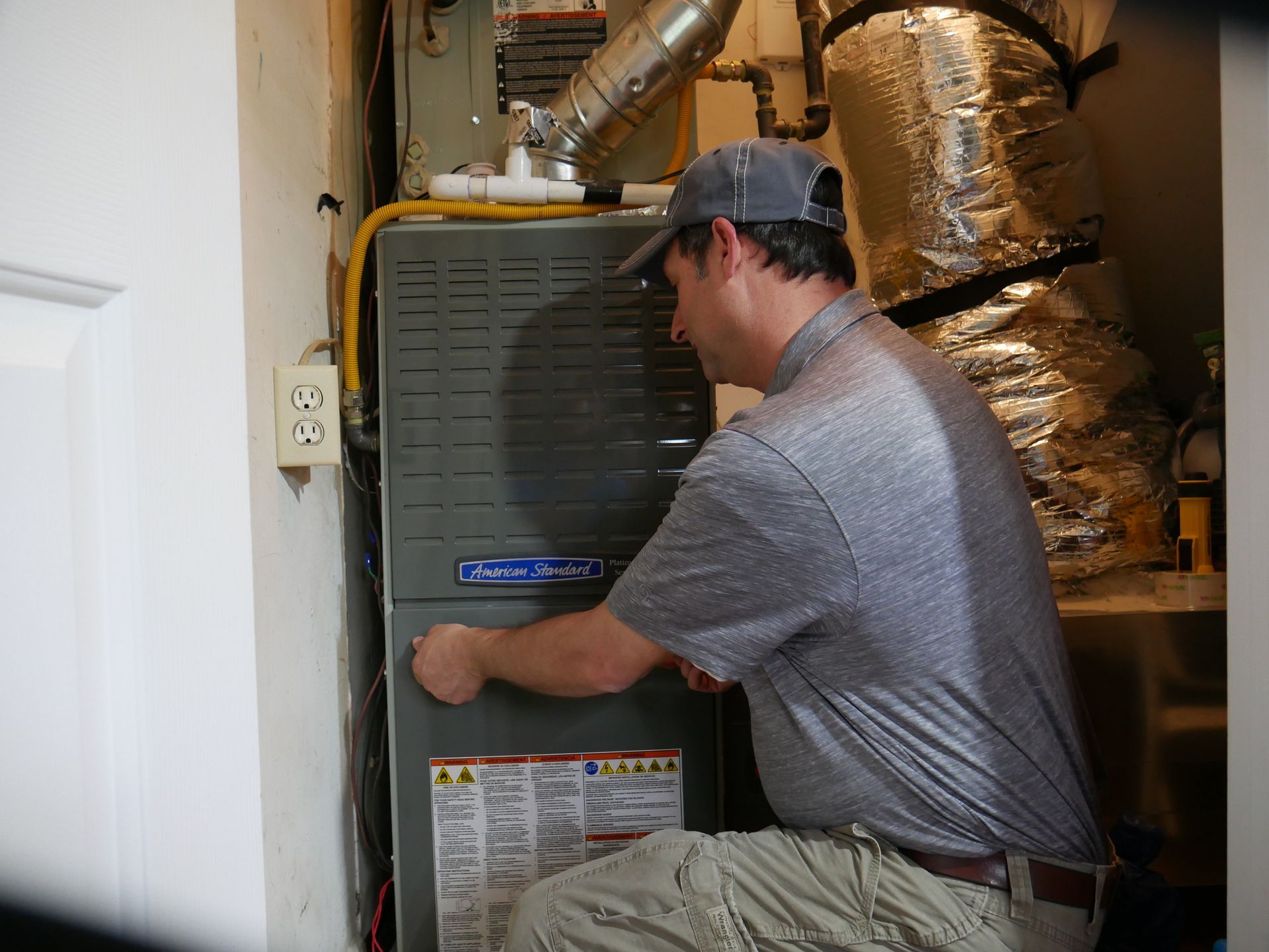 A man is talking to two people in front of an air conditioner.