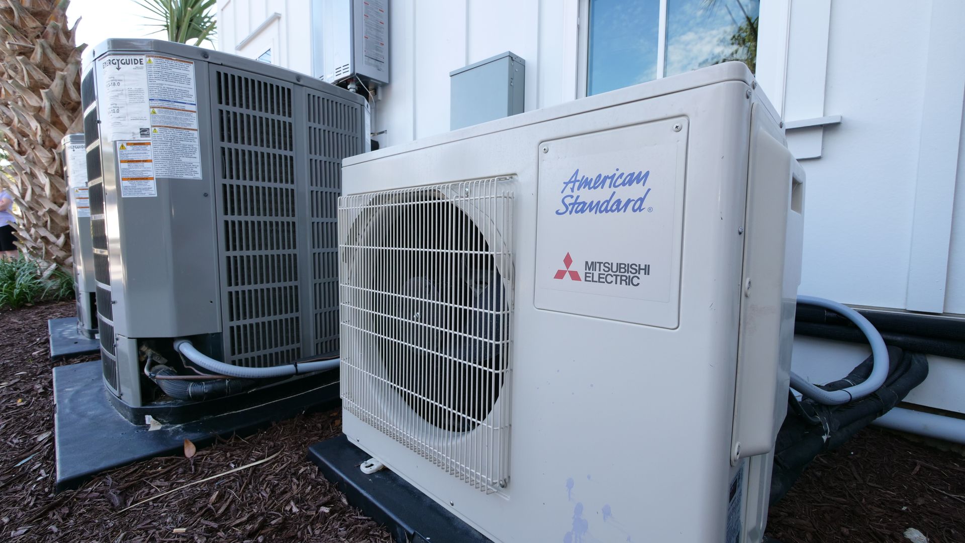 two air conditioners are sitting next to each other on the side of a building .