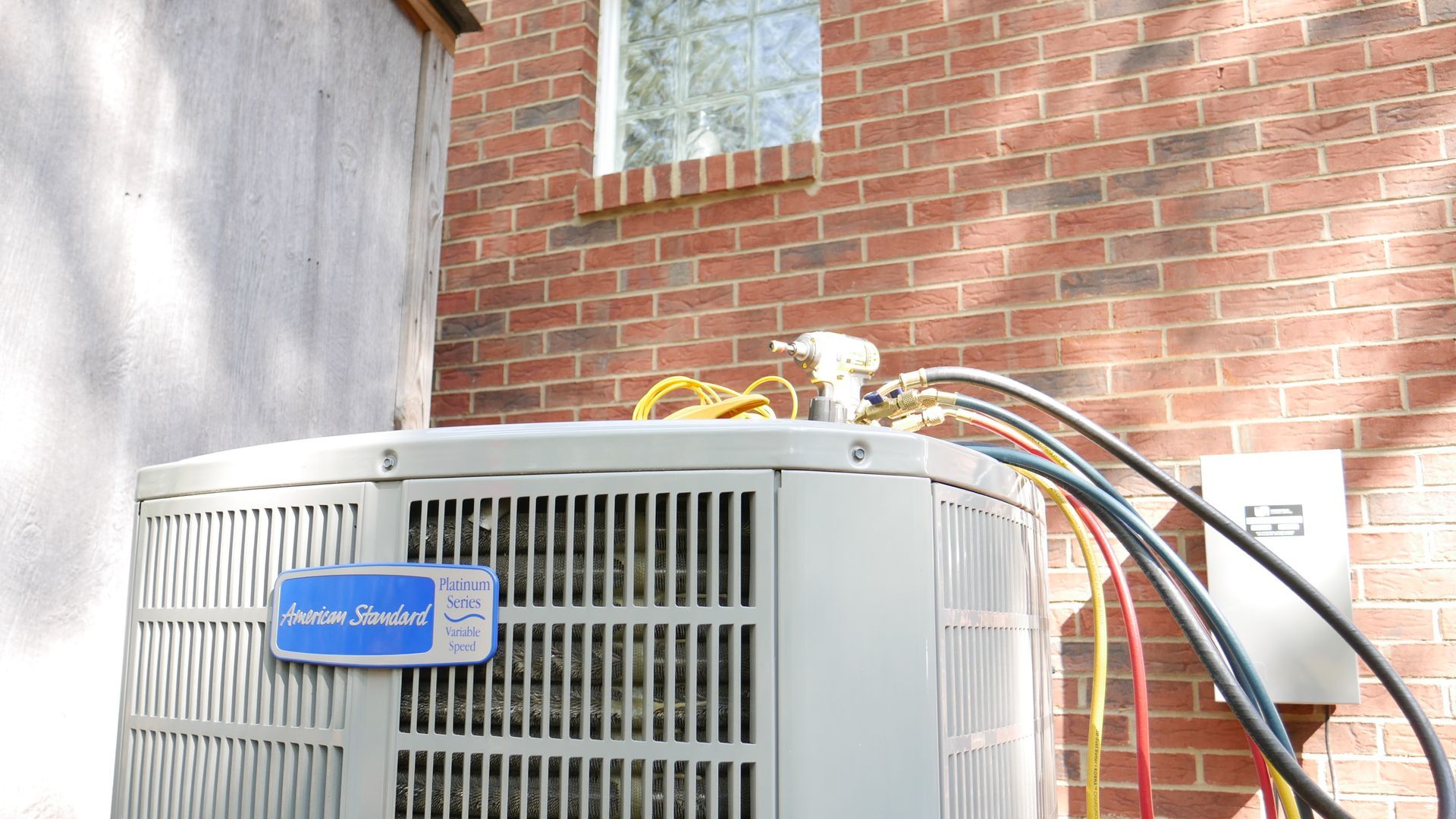 a white air conditioner is sitting on the side of a brick building .