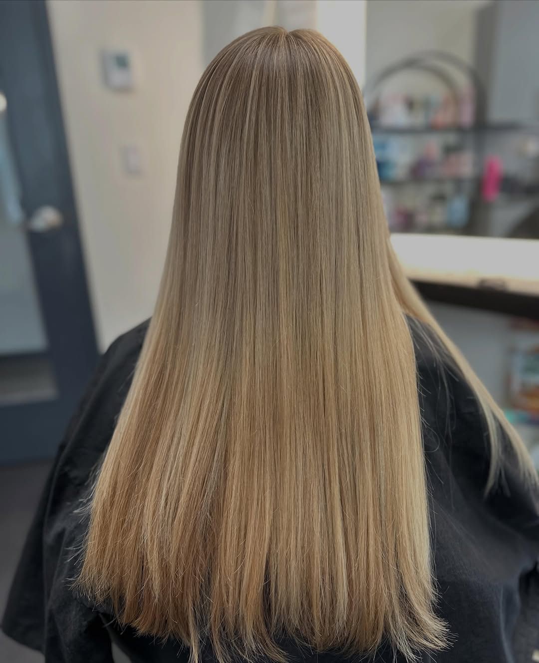 Back view of straight, shoulder-length blonde hair in a salon setting