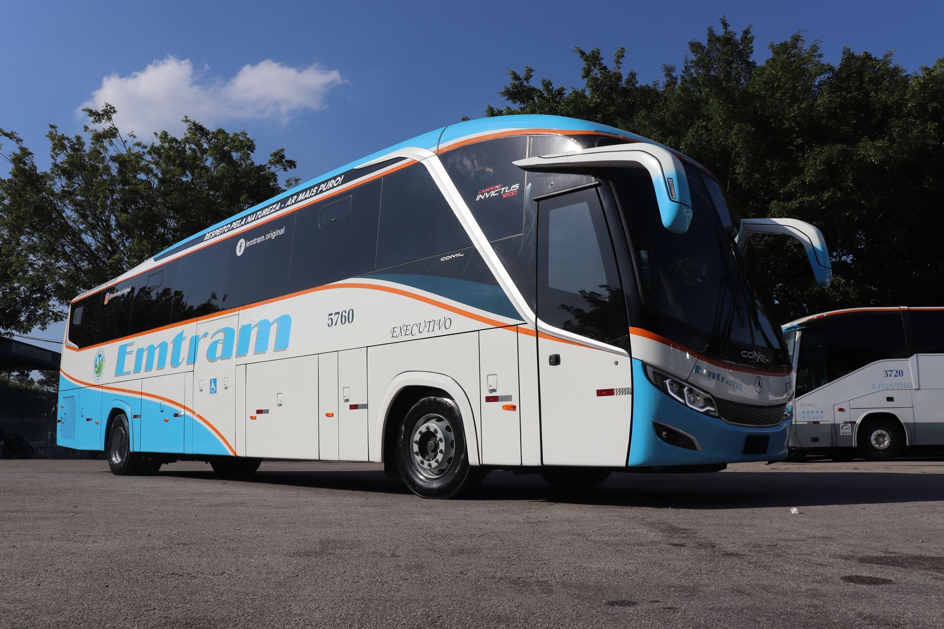 Ônibus FlixBus branco e azul estacionado em um terreno sob um céu claro.