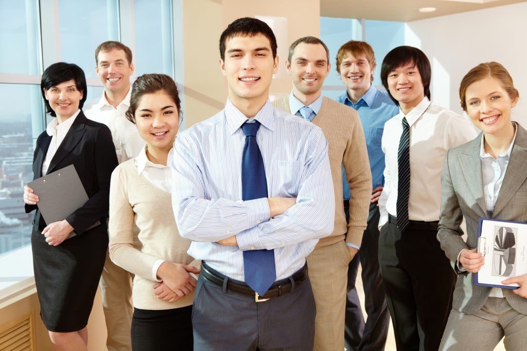 Group of businesspeople, smiling, posing in office setting.