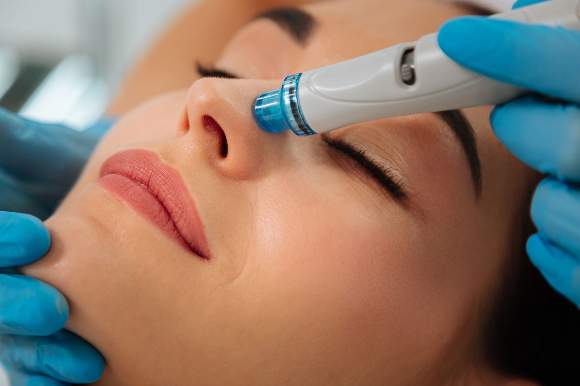 A woman is getting a facial treatment with a machine on her face.