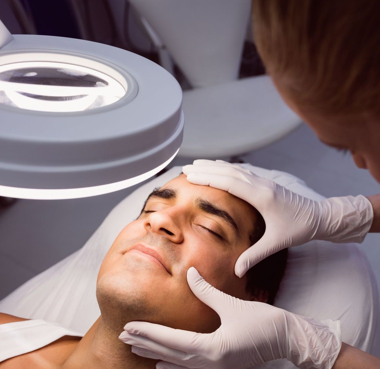 A man is getting his face examined under a magnifying glass