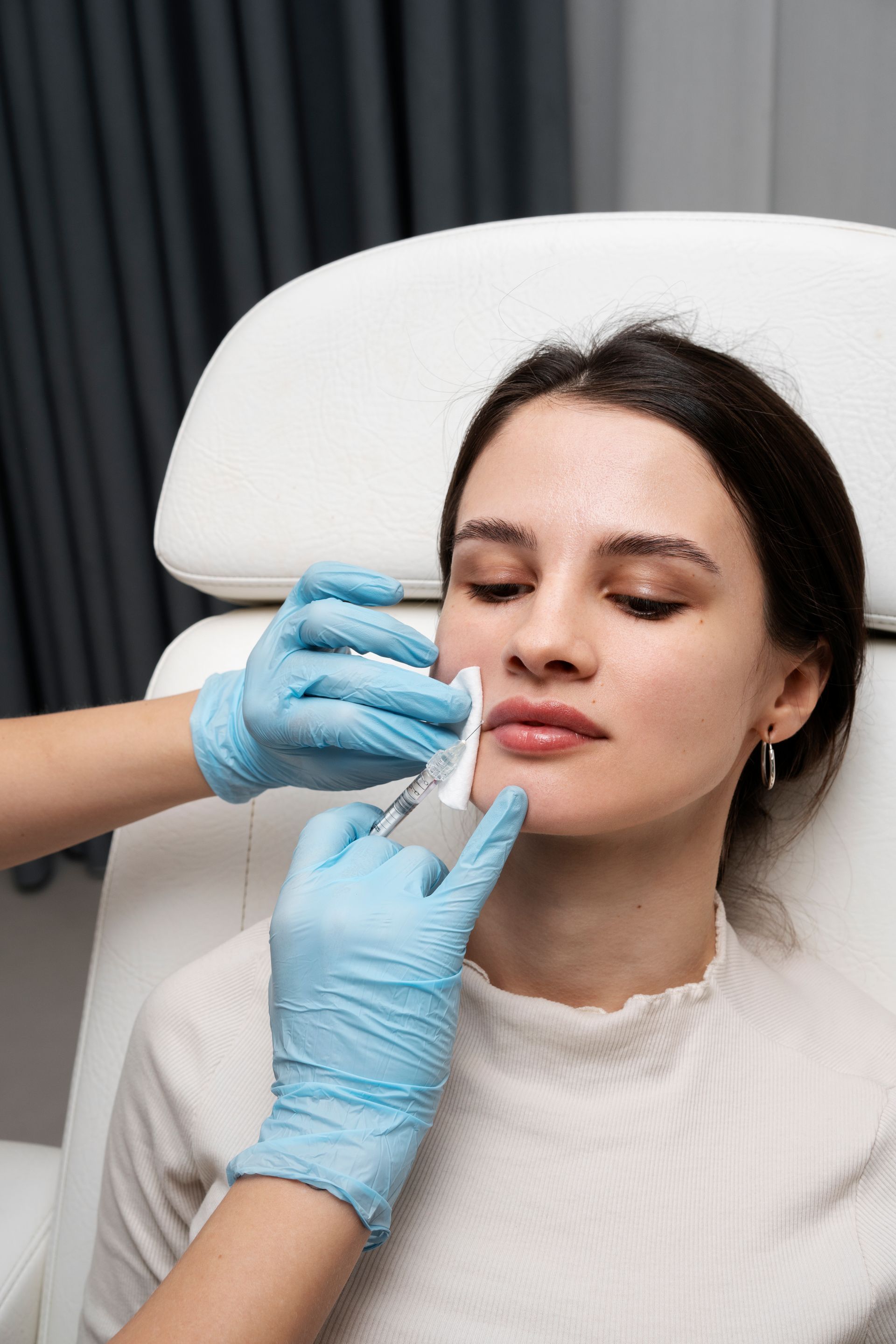 A woman is getting a botox injection in her lips.