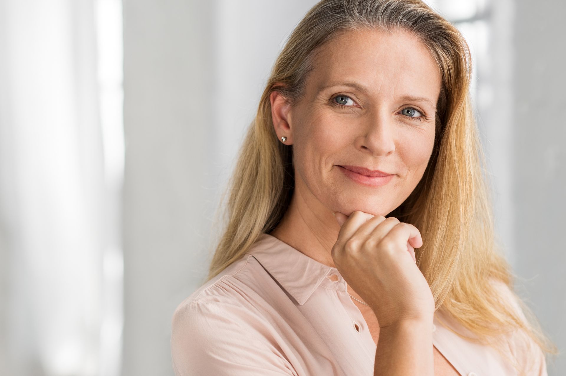 A woman is smiling with her hand on her chin.