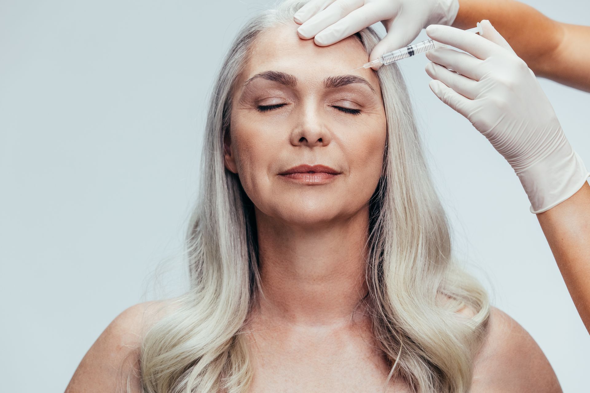 A woman is getting a botox injection in her forehead.