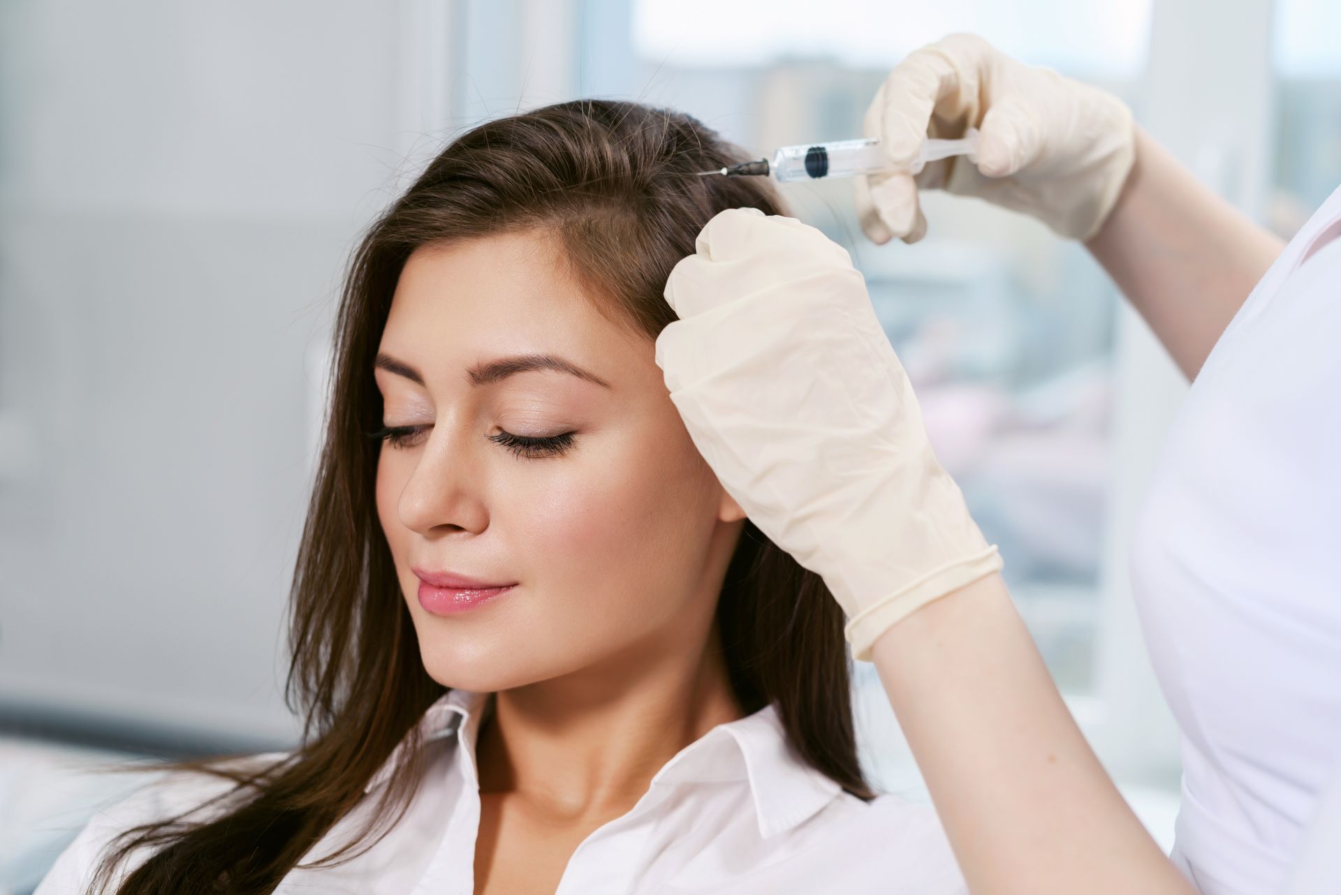 A woman is getting a hair treatment at a salon.