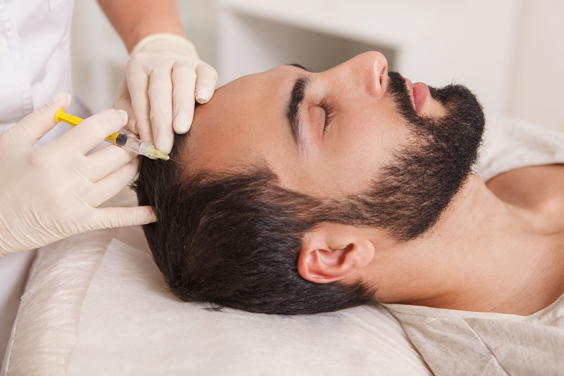 A man with a beard is getting a botox injection in his head.