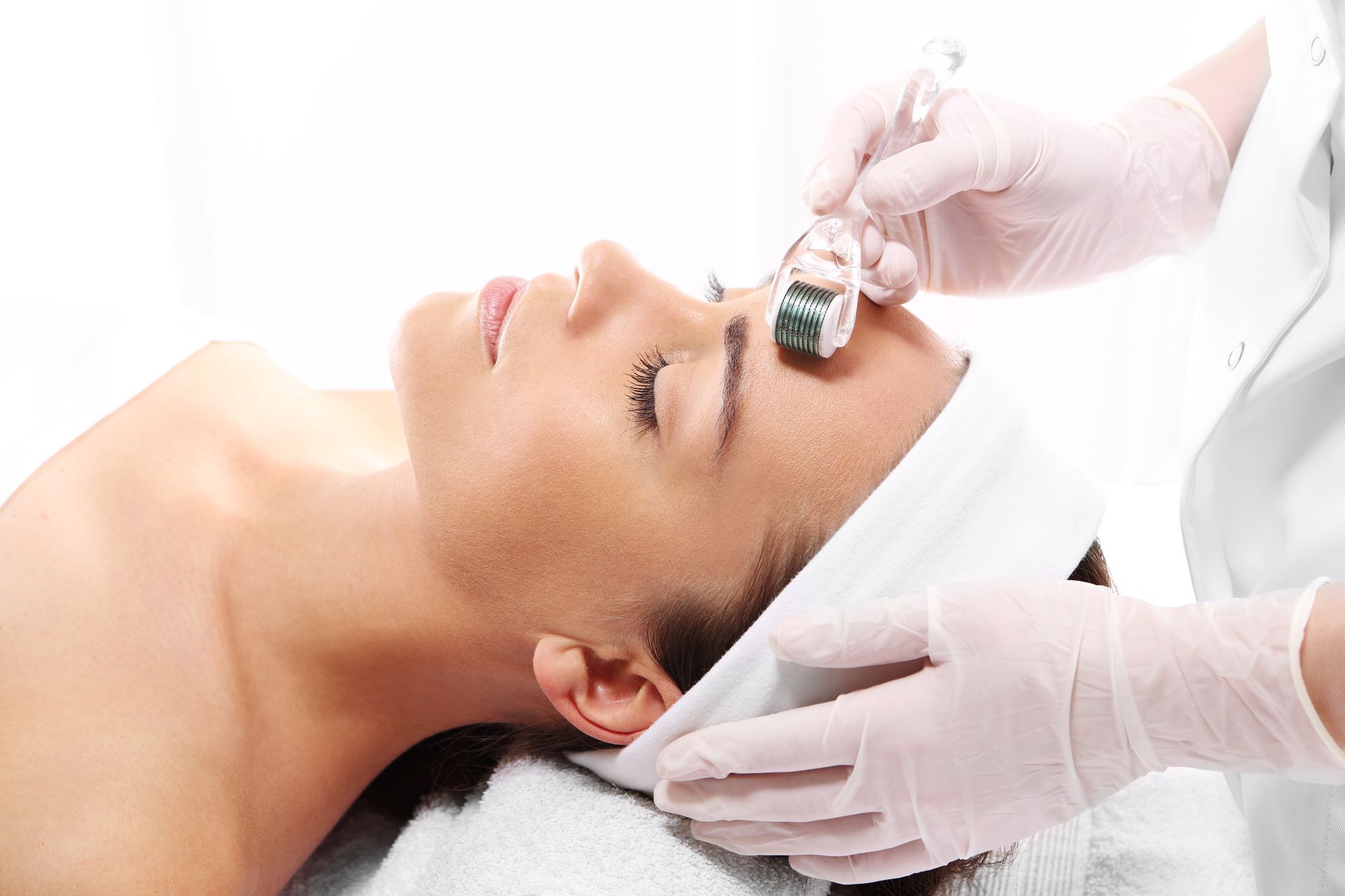 A woman is getting a facial treatment with a roller on her face.