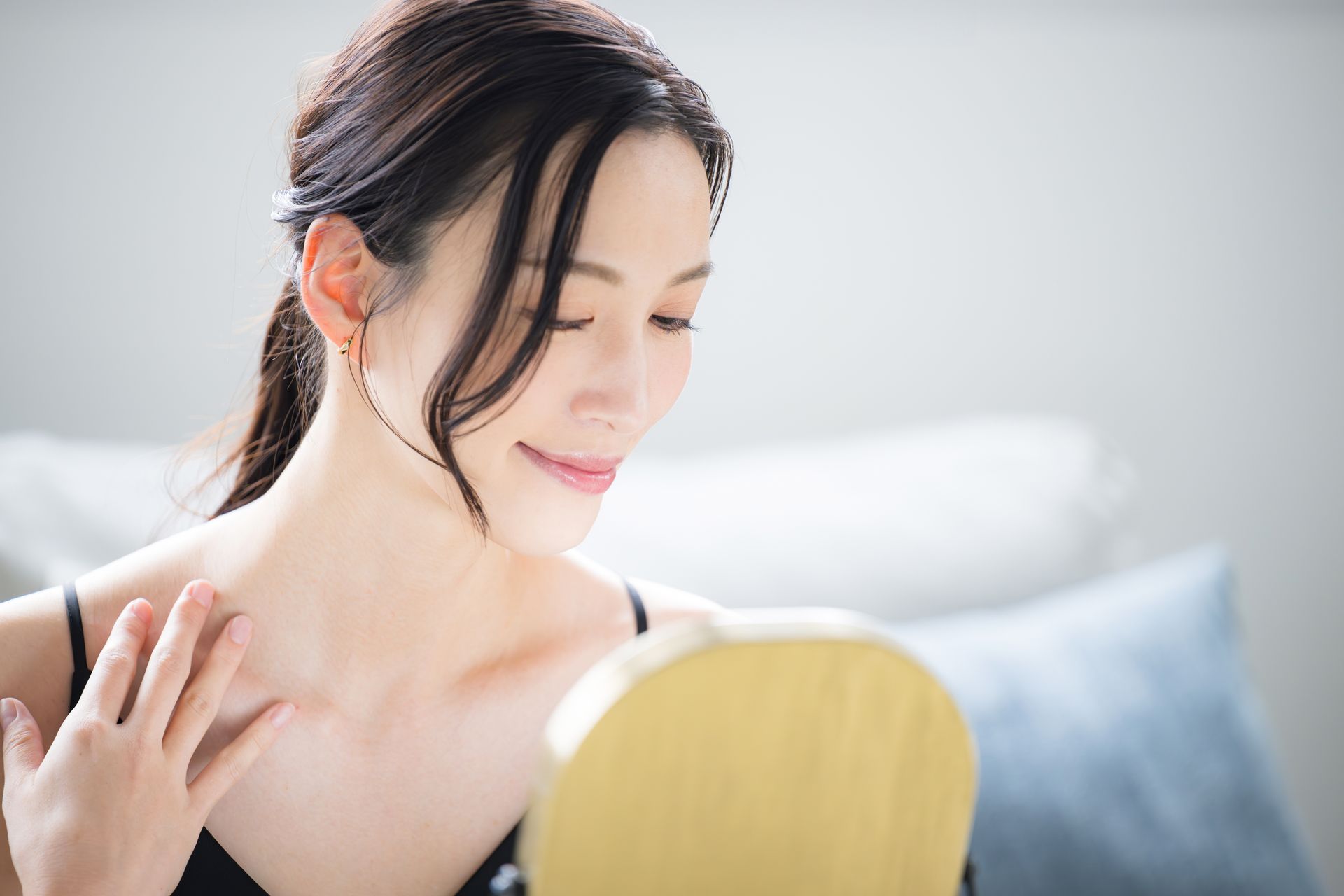 A woman is looking at her neck in a mirror.