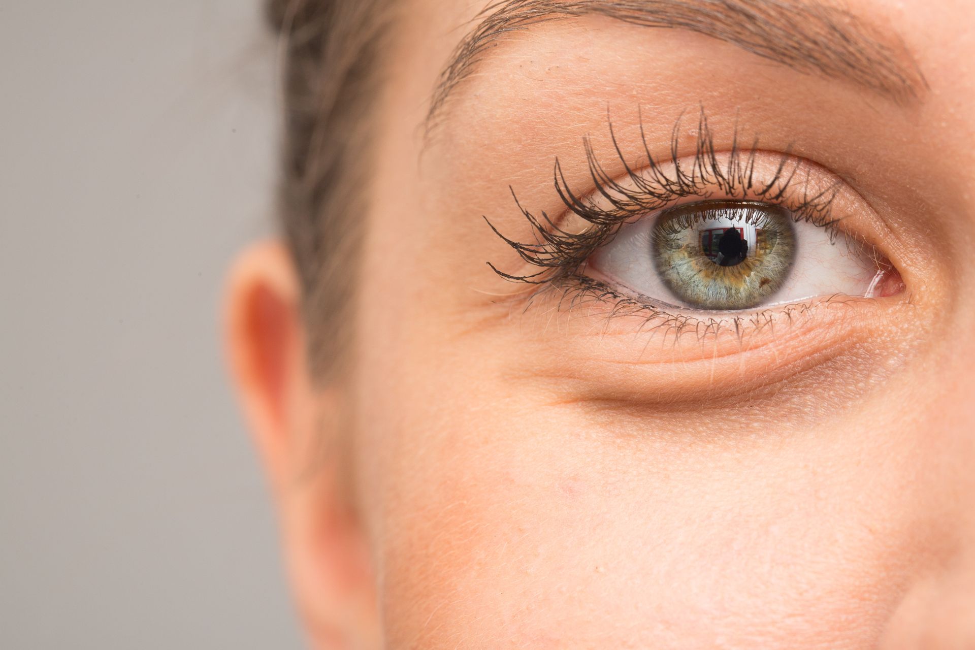 A close up of a woman 's green eye with mascara.