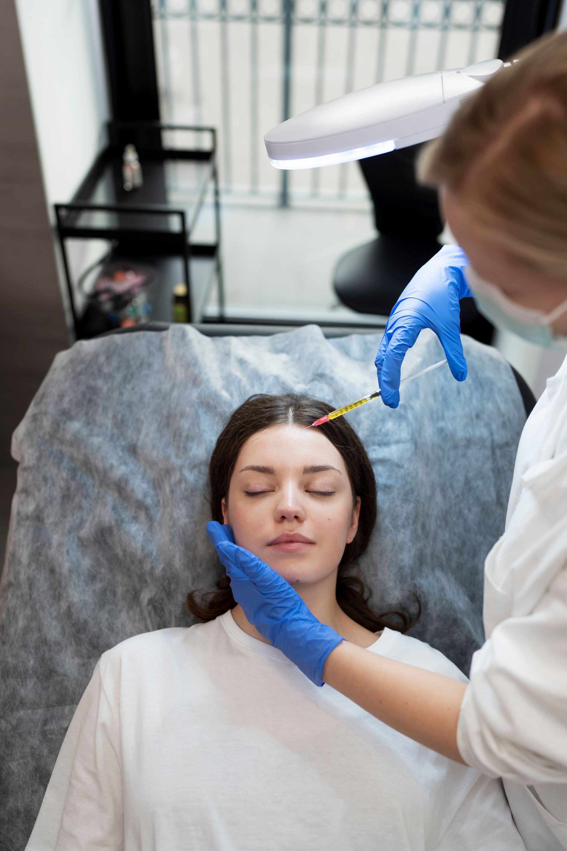A woman is getting an injection in her head in a beauty salon.