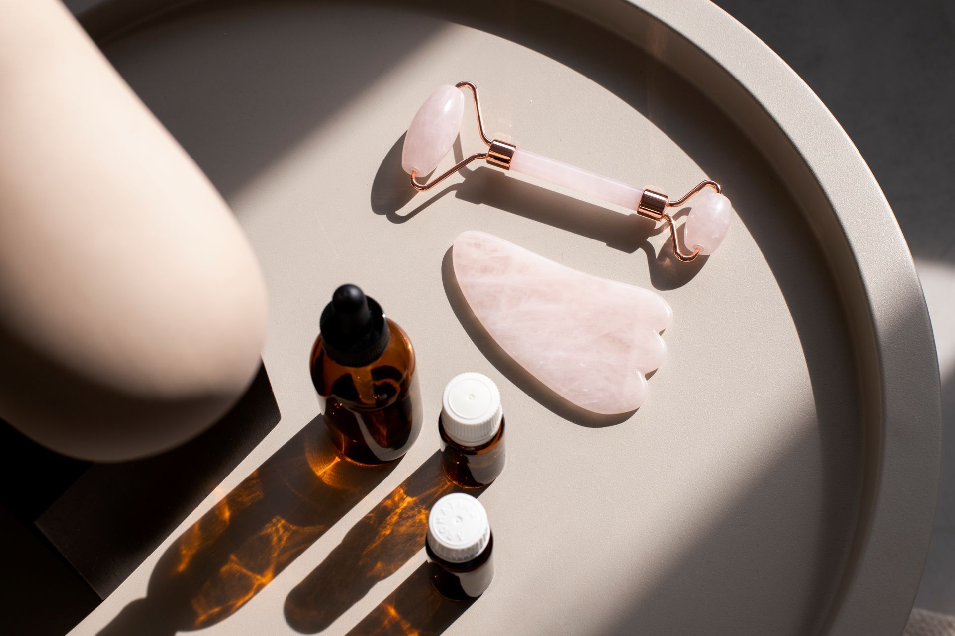 A table topped with bottles , a roller , and a gua sha.