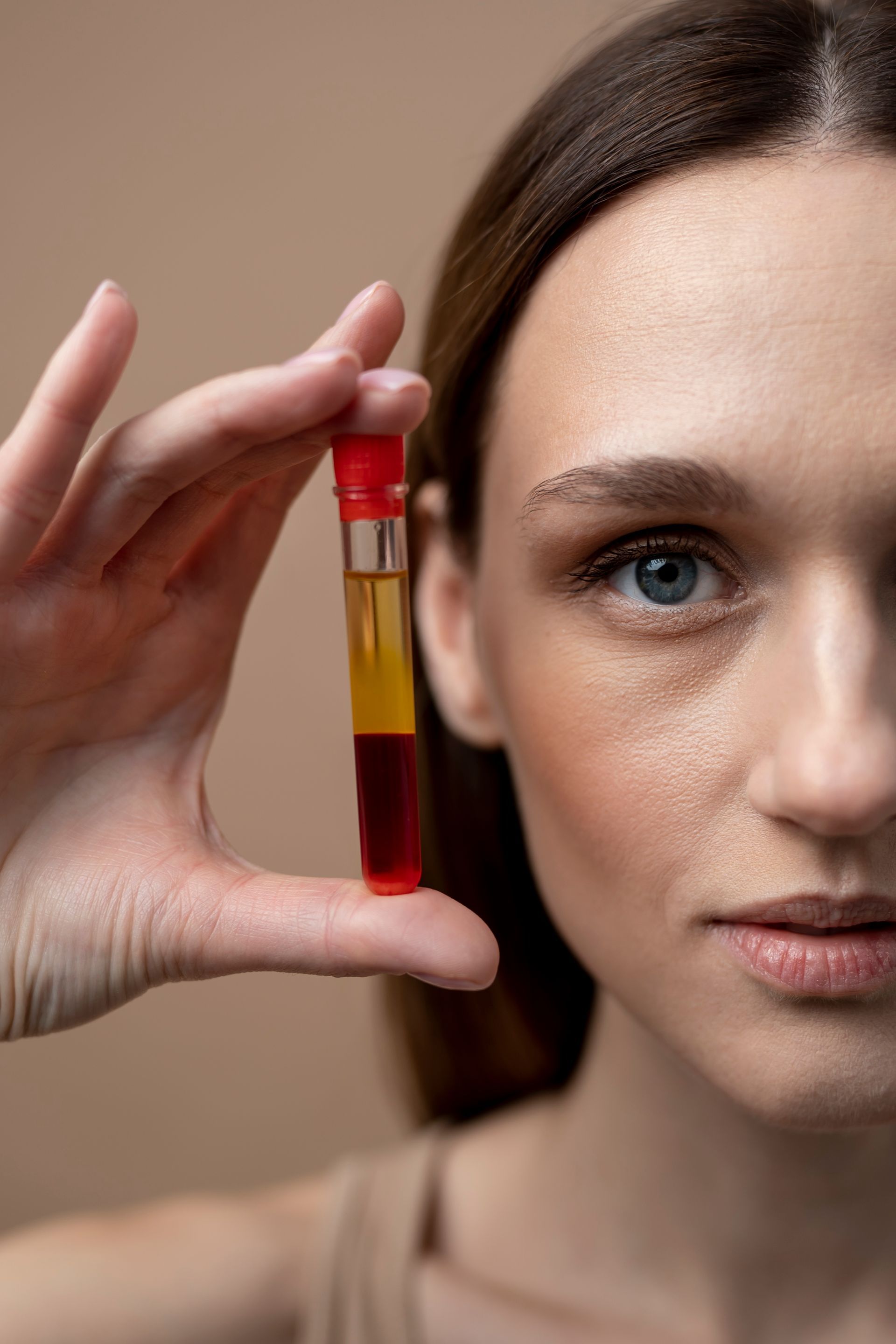 A woman is holding a test tube with a red liquid in it.