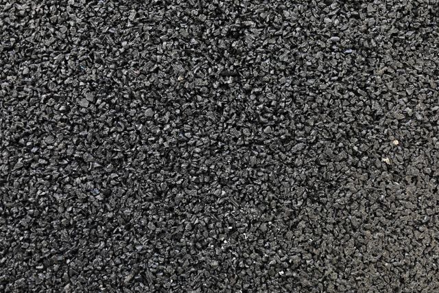 Close-up of gray asphalt pavement with a shadow in the lower right corner