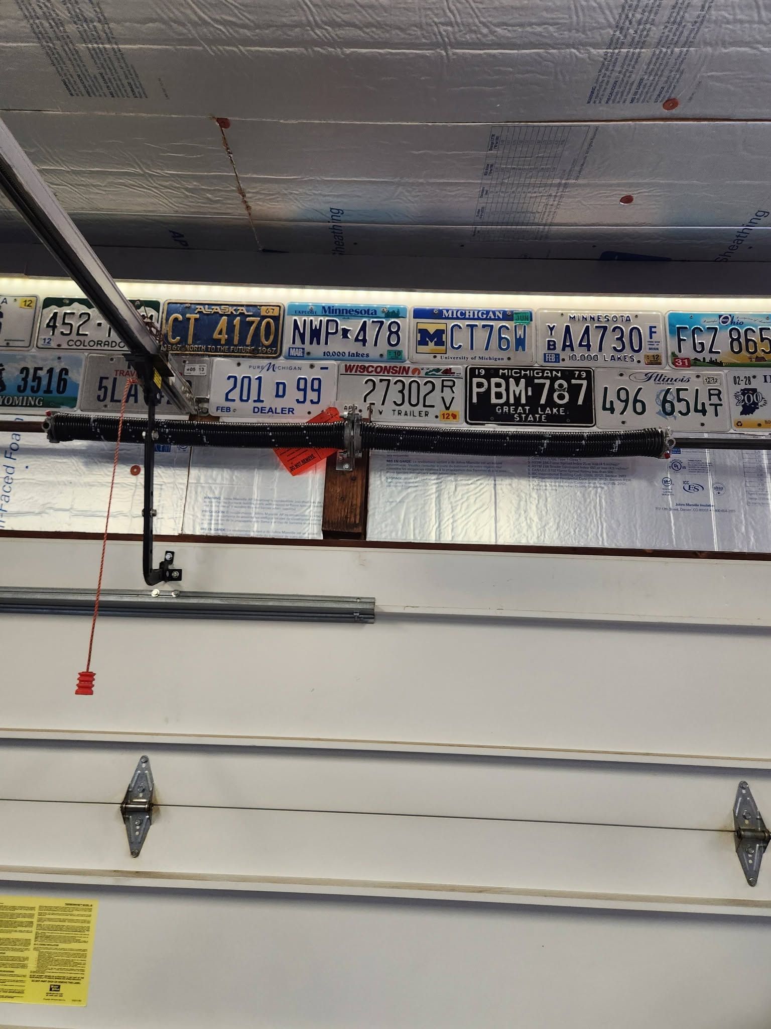 Garage with white sectional door and license plates displayed above it