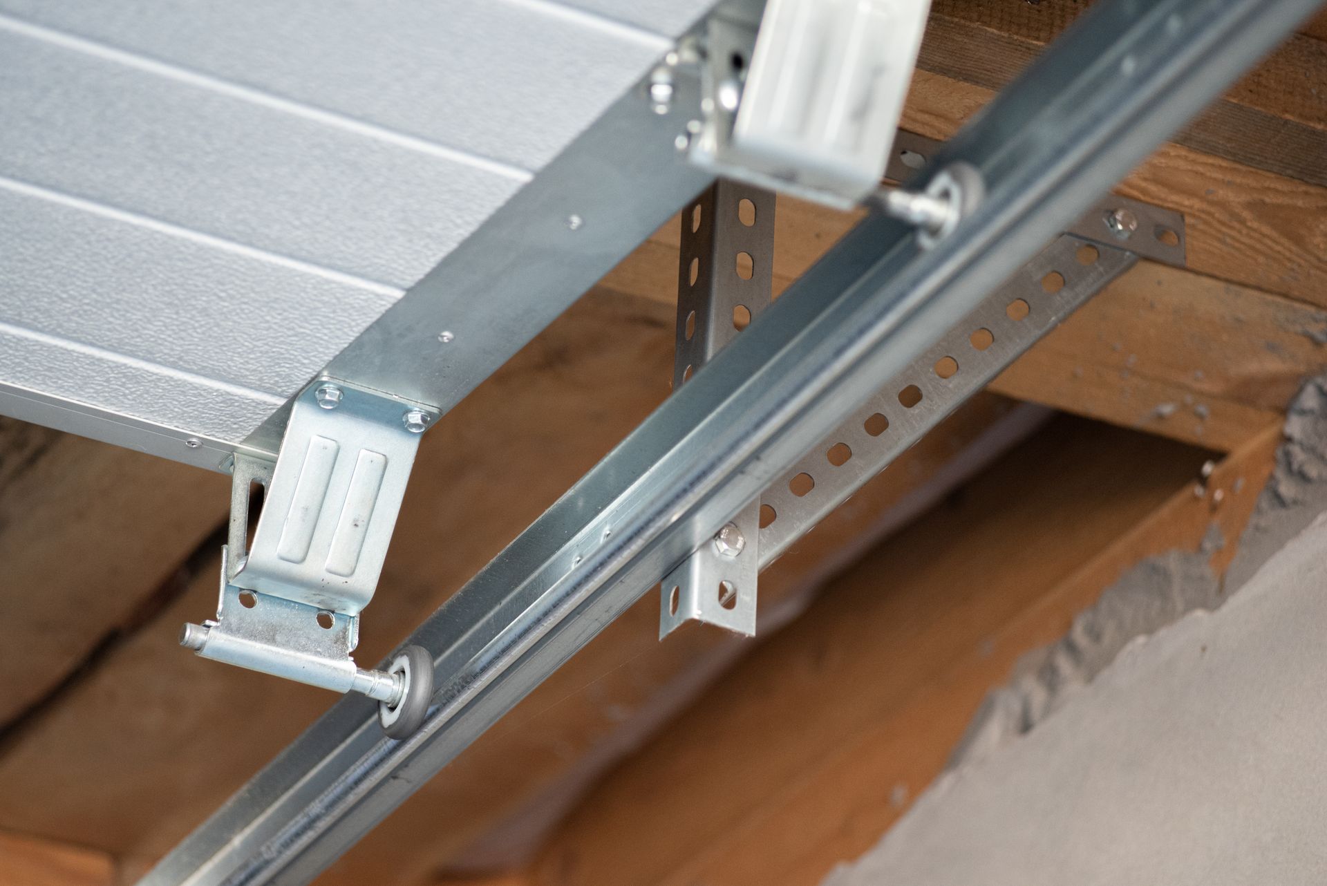 Garage door track and opener bracket attached to a wooden beam ceiling