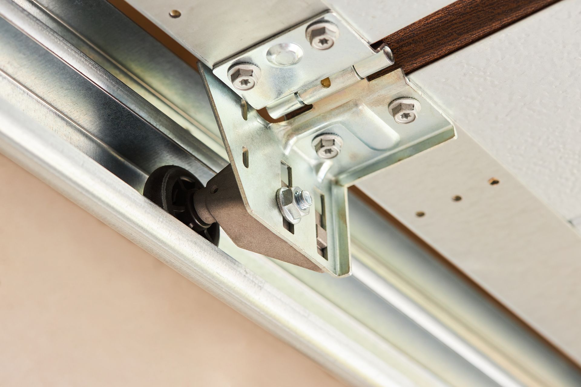 Close-up of a metal ceiling track bracket with a wheel and mounting screws.