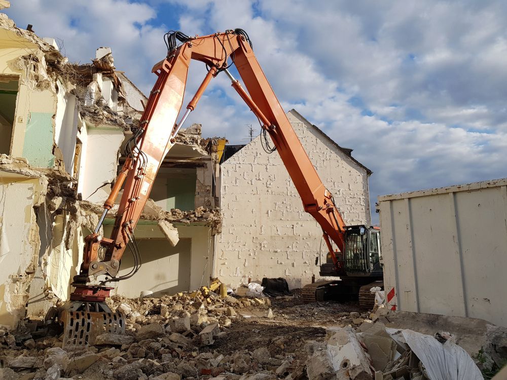 A Large Orange Excavator Is Demolishing A Building — ACC Excavations & Demolition Pty Ltd In Albion Park, NSW