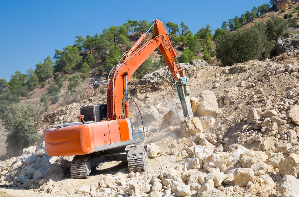 A Large Orange Excavator Is Moving Rocks In A Quarry — ACC Excavations & Demolition Pty Ltd In Oak Floats, NSW