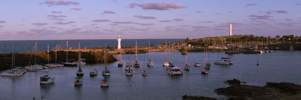 A Harbor With Boats And A Lighthouse In The Background — ACC Excavations & Demolition Pty Ltd In Wollongong, NSW