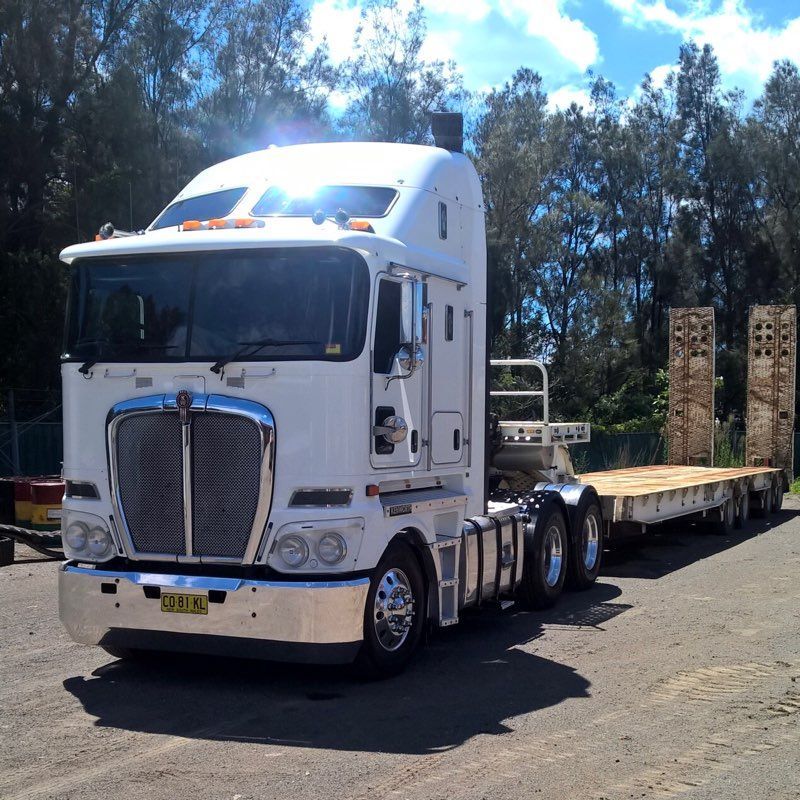 A Kenworth Semi Truck With A Flatbed Trailer Attached — ACC Excavations & Demolition Pty Ltd In Albion Park, NSW
