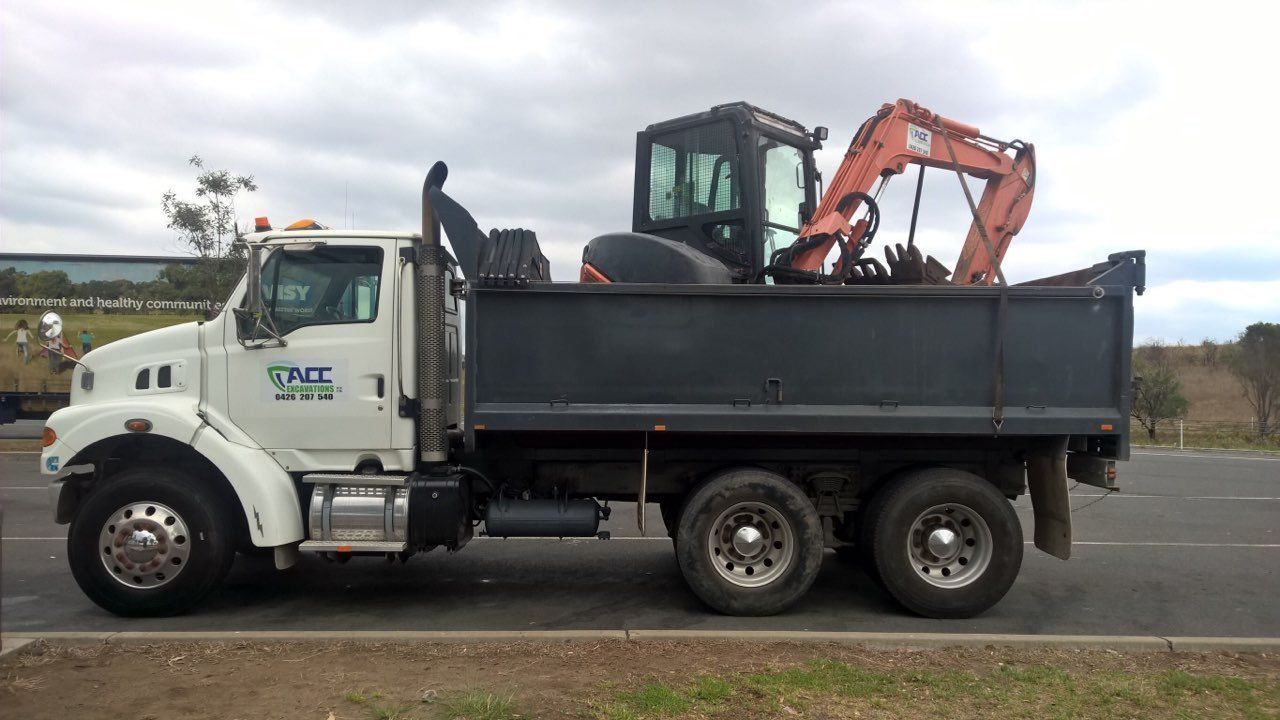 A Dump Truck With An Excavator In The Back Is Parked— ACC Excavations & Demolition Pty Ltd In Albion Park, NSW