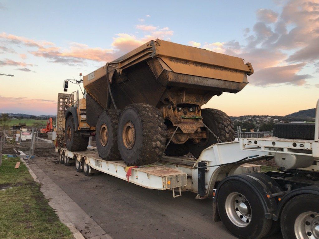 A Large Dump Truck Is Being Transported On A Trailer — ACC Excavations & Demolition Pty Ltd In Shellharbour, NSW
