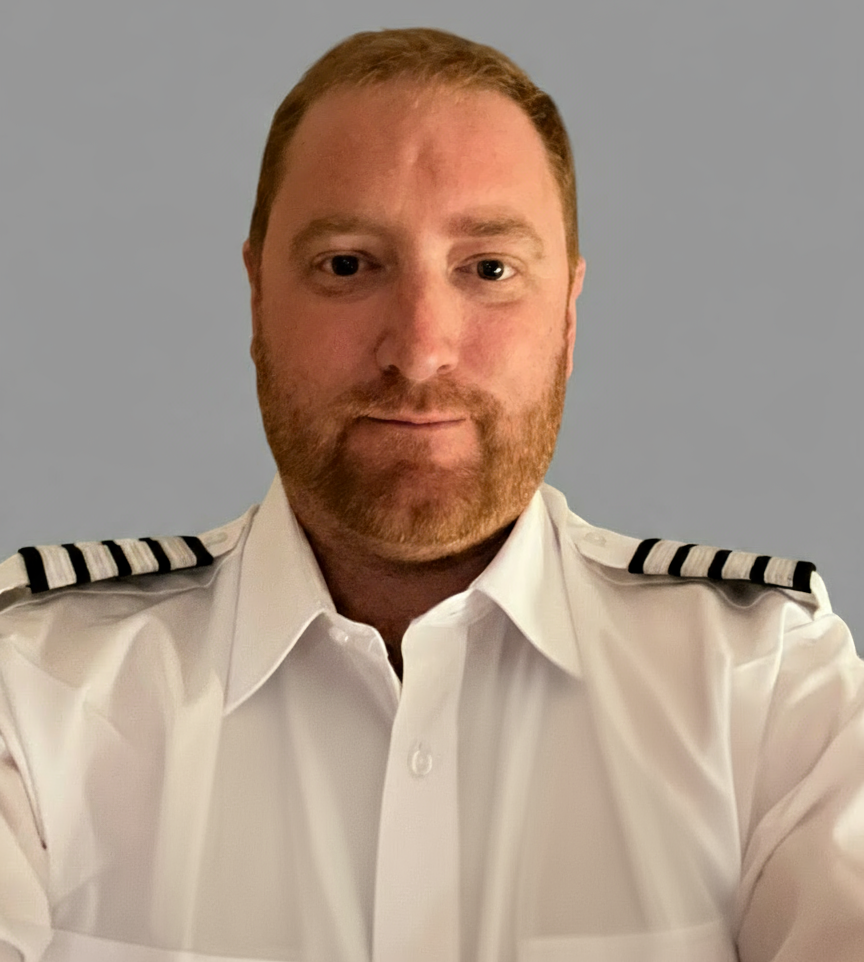 Man in white uniform shirt with shoulder stripes, looking at the camera.