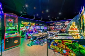 Colorful arcade with pinball machines, neon lights, and arcade cabinets in a game room