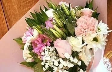 A Bouquet of Flowers Wrapped in Pink Paper is Sitting on a Wooden Table — Flower Hunt in Robina, QLD