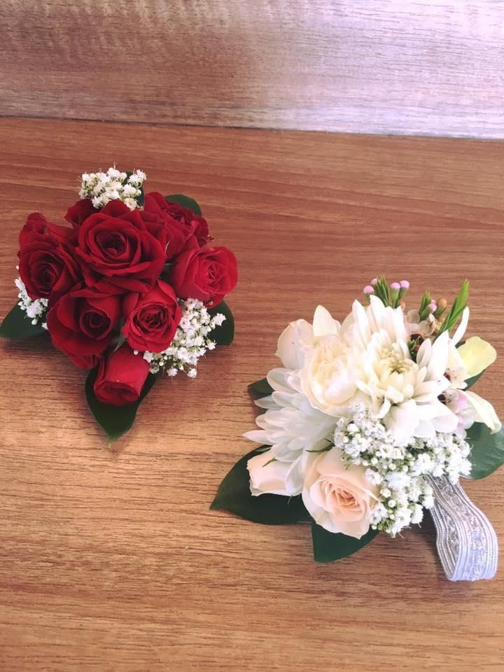 Two Wrist Corsages With Red Roses and White Flowers on a Wooden Table — Flower Hunt in Robina, QLD