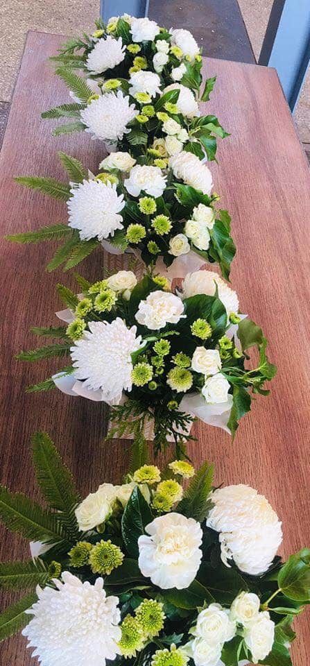 A Row of White Flowers Sitting on Top of a Wooden Table — Flower Hunt in Robina, QLD