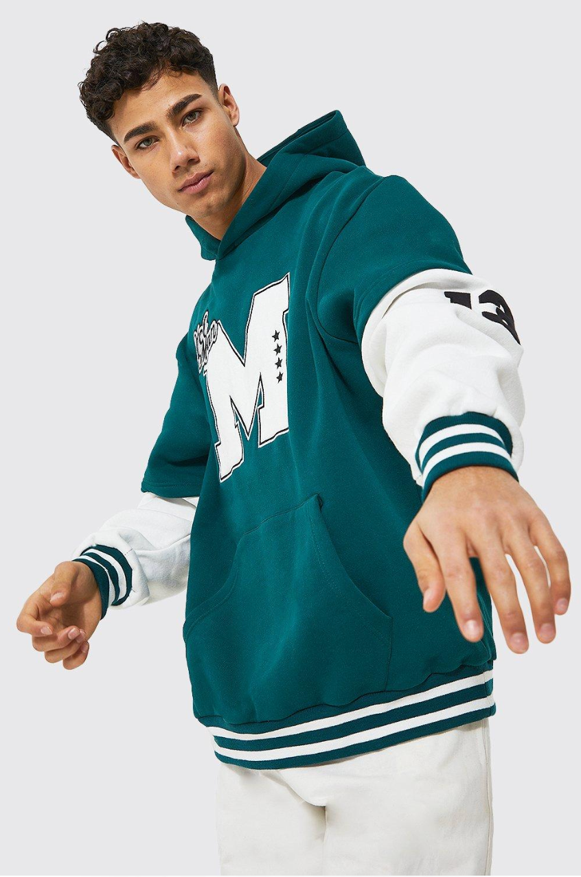 A man wearing a green hoodie with the letter m on it