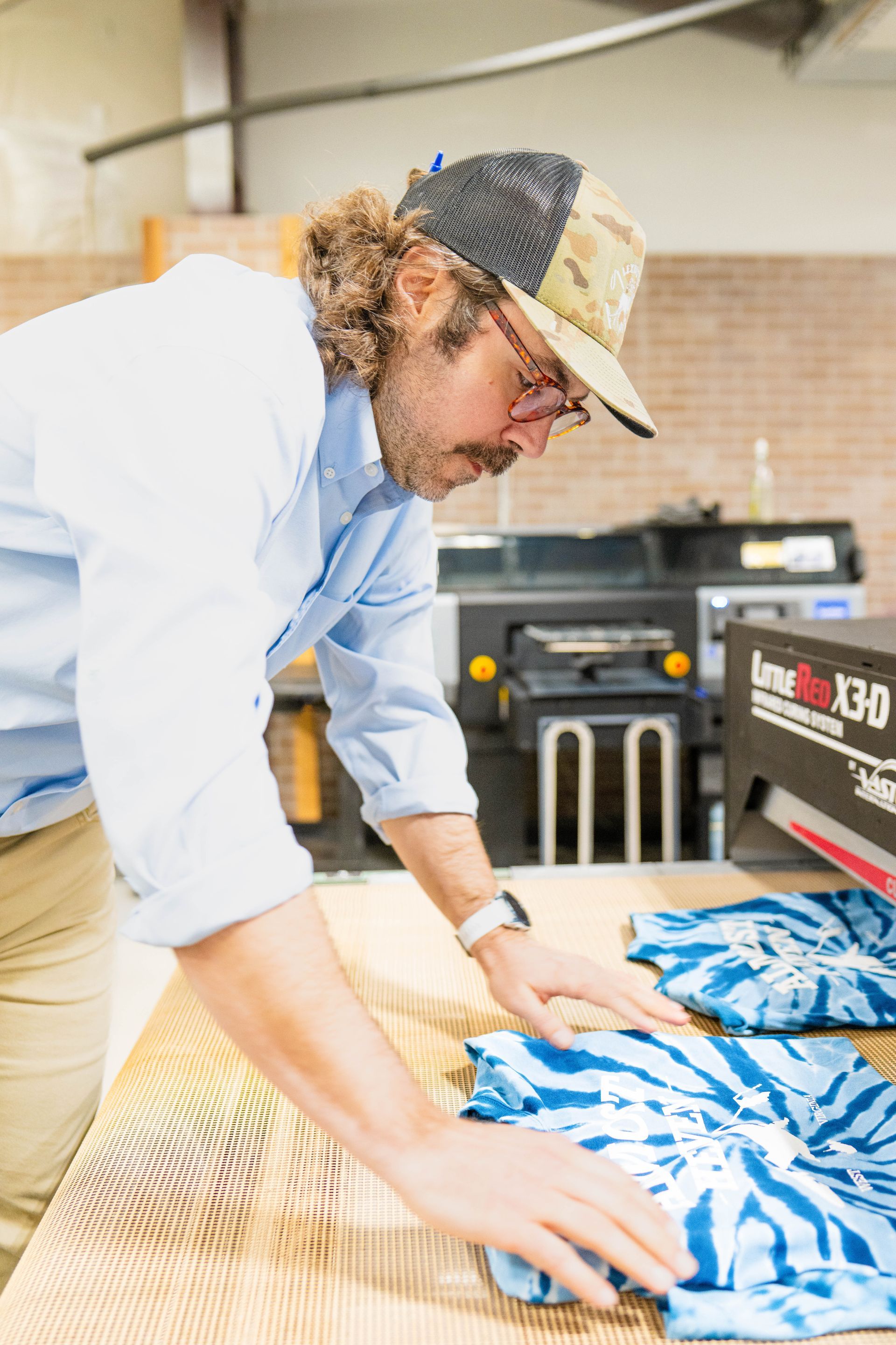 A man is standing at a table looking at a piece of fabric.