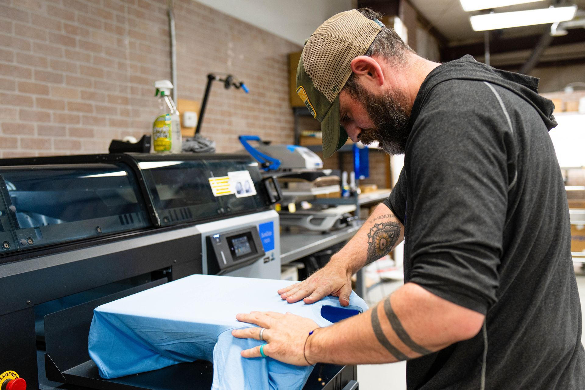 A man is printing a shirt on a machine in a factory.