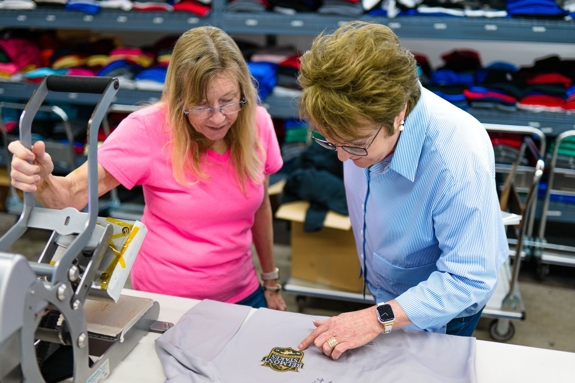 Two women are working on a machine in a factory.