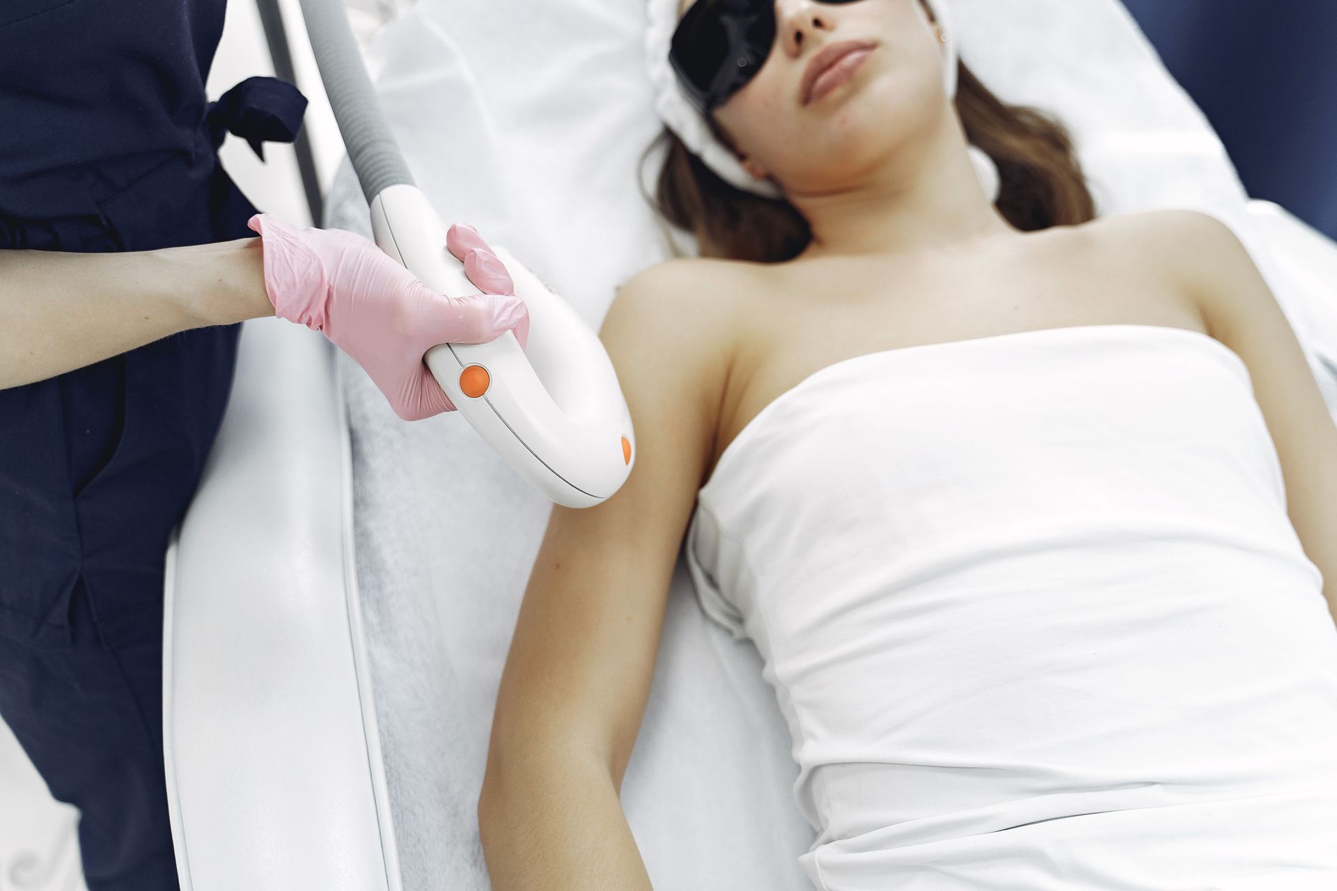 Medical professional using a handheld laser device near a patient lying on a treatment table