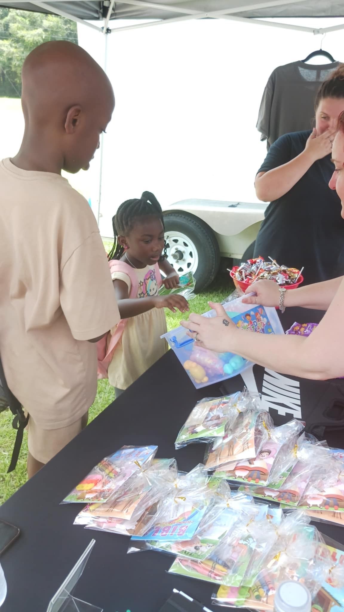 A group of people are standing around a table with bags of candy.