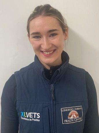 A woman wearing a blue vest is smiling for the camera.