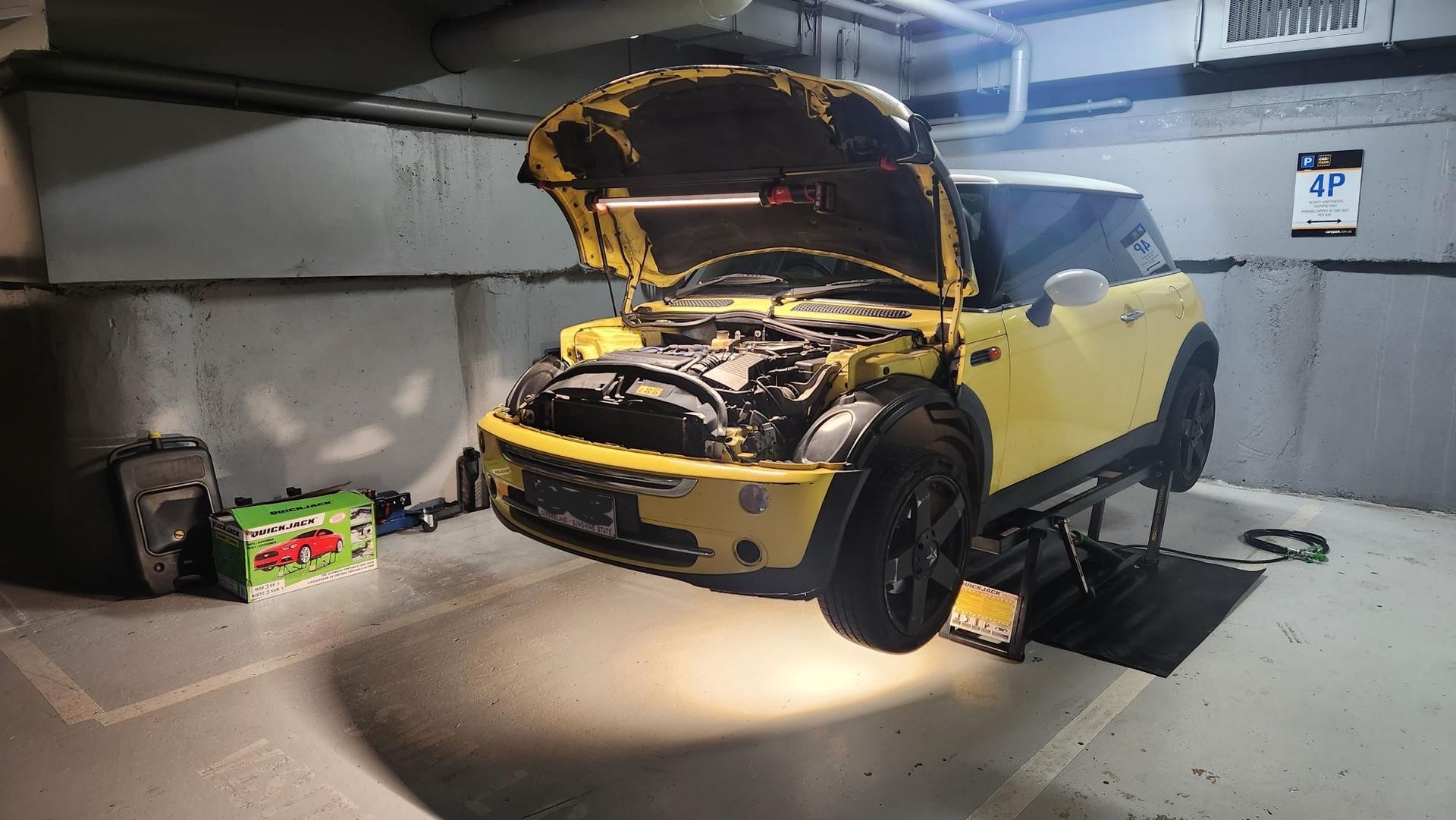 A Yellow Car With the Hood Open is Sitting on a Lift in a Garage — Warrmech Mechanical in Tweed Heads South, NSW